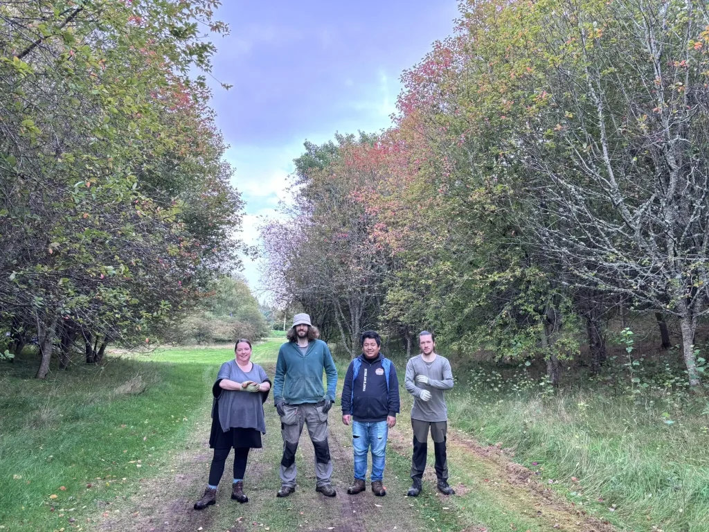Four volunteers at Buddhist Meditation Centre smiling between the trees.