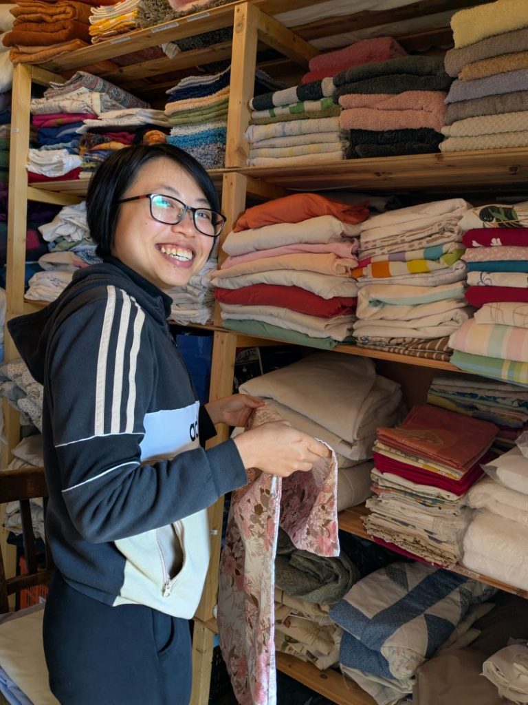 International volunteer Winnie smiling while folding laundry.