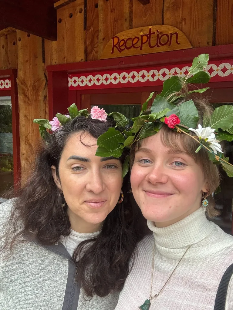 Two international female volunteers smiling wearing flower crowns.