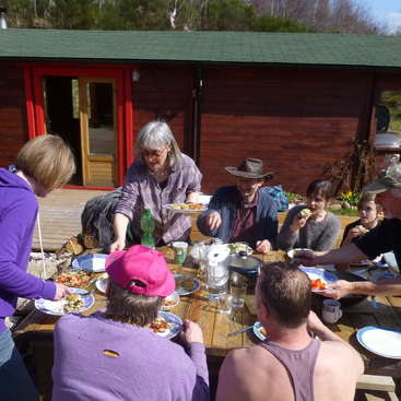 Group of local community volunteers Scottish Highlands having lunch in the sun.